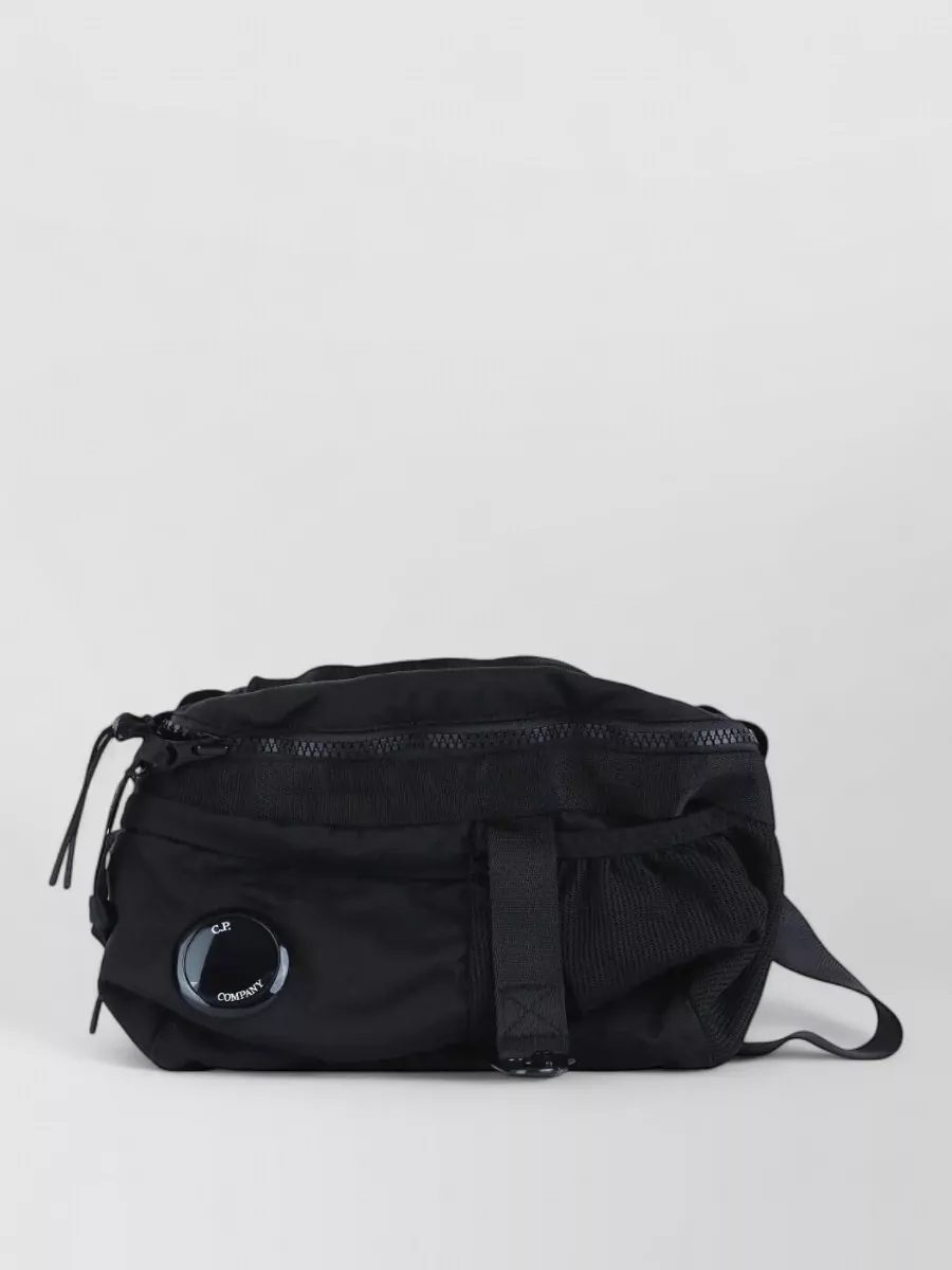 C.P. Company Nylon belt bag — The compact C.P. Company crossbody with lens detail locks into the brand story and utility feel without adding bulk, mirroring the subtle hardware on the cargos.