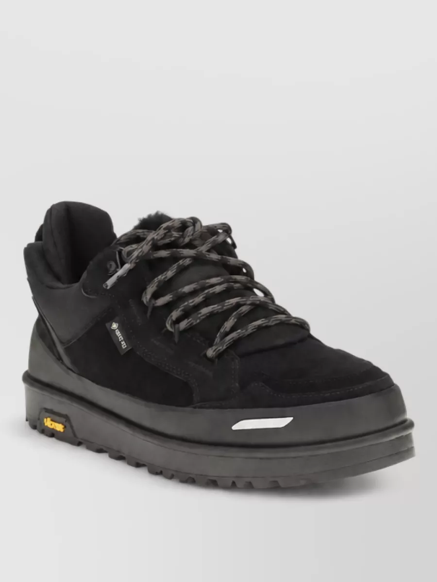 Ugg Leather low-top sneakers — The black New Balance trail runners echo the jacket’s technical energy and charcoal tones, giving the outfit a cohesive urban-outdoor feel and practical grip for cold-weather streets.