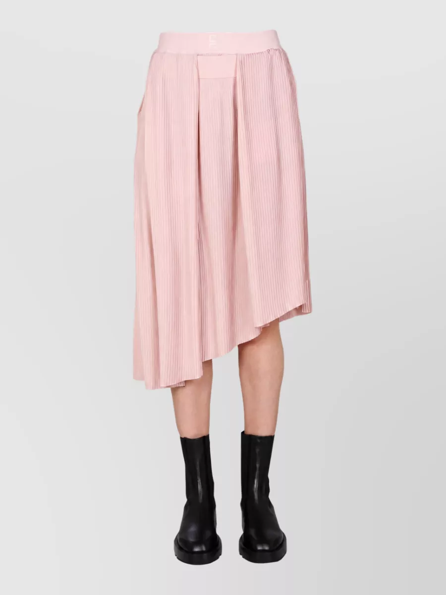 Givenchy Pleated skirt — The Givenchy blush asymmetric pleated midi mirrors the top’s soft ivory romance while adding polished volume at the hip and a fluid, dressy silhouette that suits the formality of the sculpted bow bralette.