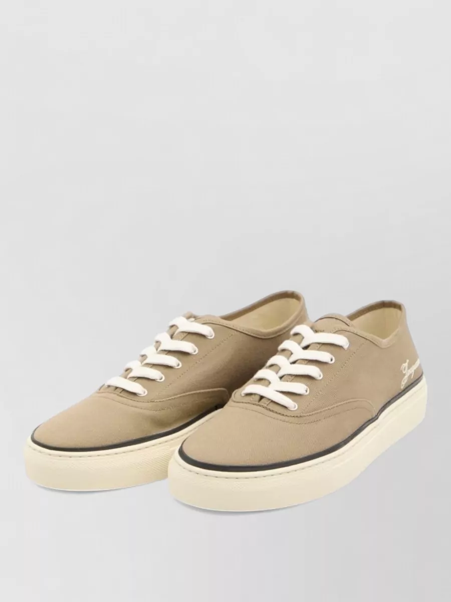 Jacquemus Cotton low-top sneakers — The Jacquemus taupe canvas sneakers echo the earthy notes in the shirt, keep the mood street-preppy, and offer an airy, summer-appropriate finish that complements tailored shorts.