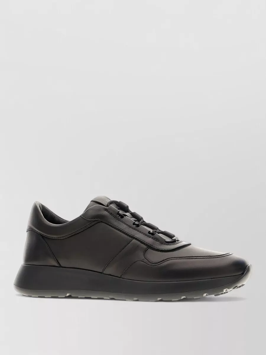 Tod's Leather sneakers — The black Tod’s city sneakers read sleek and polished enough for tailoring while keeping the outfit relaxed, and their black-and-grey palette ties directly into the charcoal trouser.