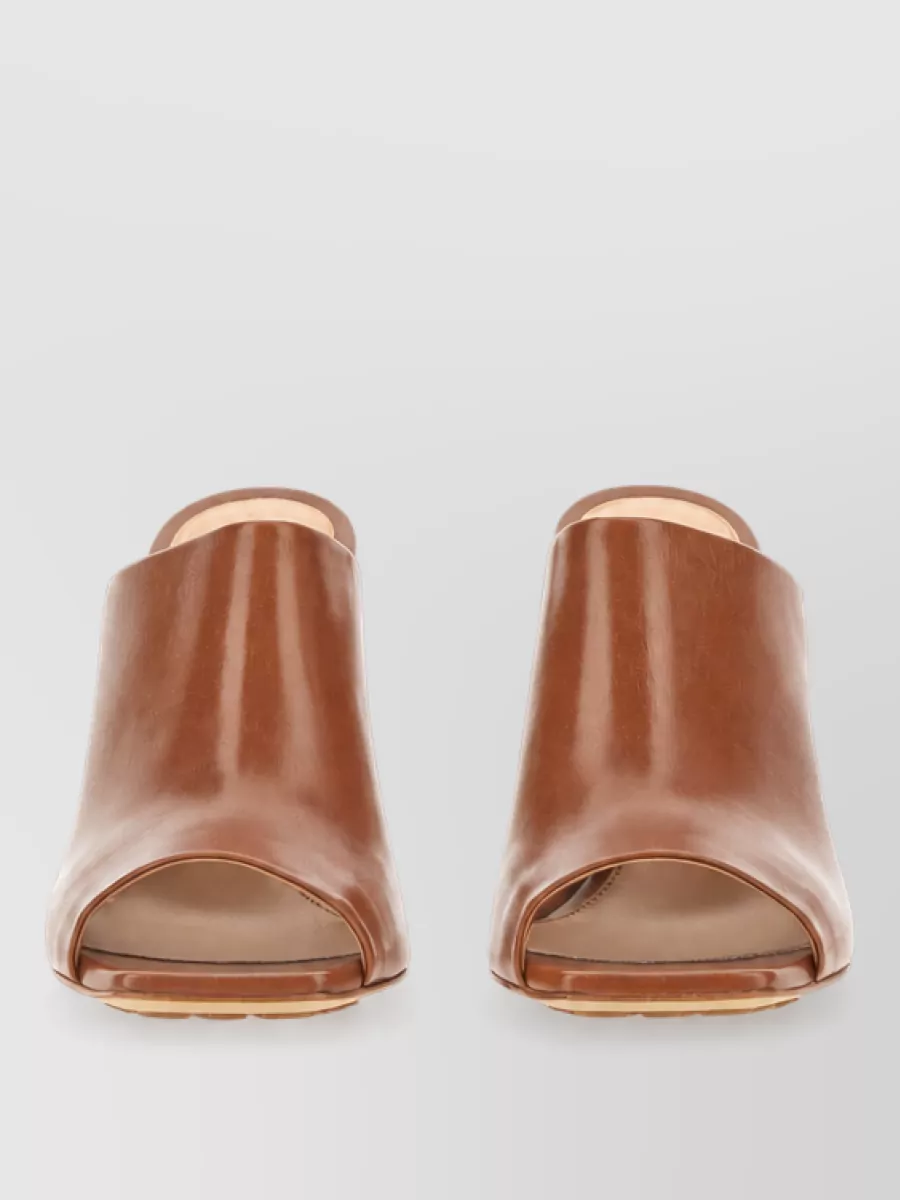 Bottega Veneta Leather knot mules — The tan block-heel mules deliver the right formality, elongate the leg under the cropped flare, and introduce a warm neutral that quietly complements peach denim and mint-detailed knitwear.