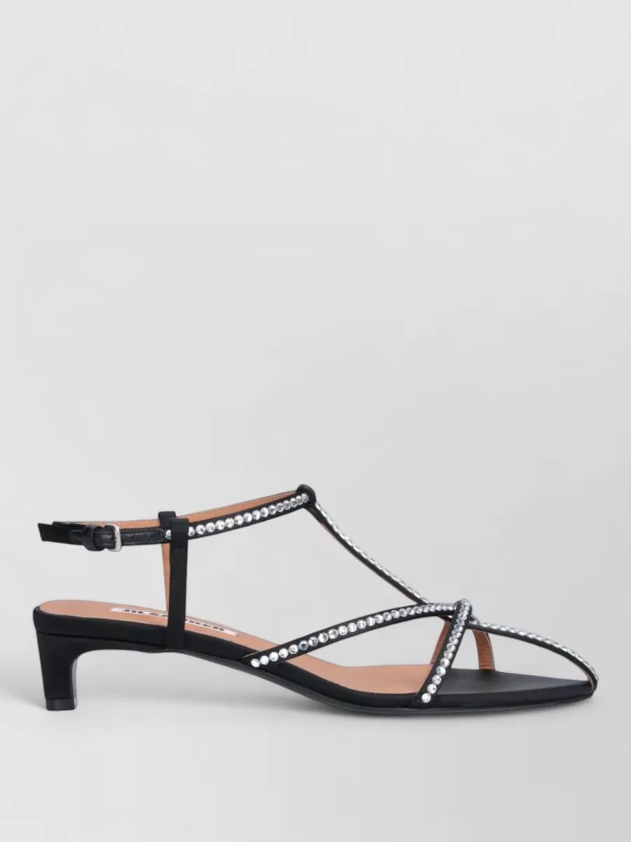Jil Sander Cage sandals — The Jil Sander black pointed kitten-heel sandals stay in the same restrained luxury register as the bag and dress, with delicate crystal straps echoing the bag’s silver hardware without overpowering it.
