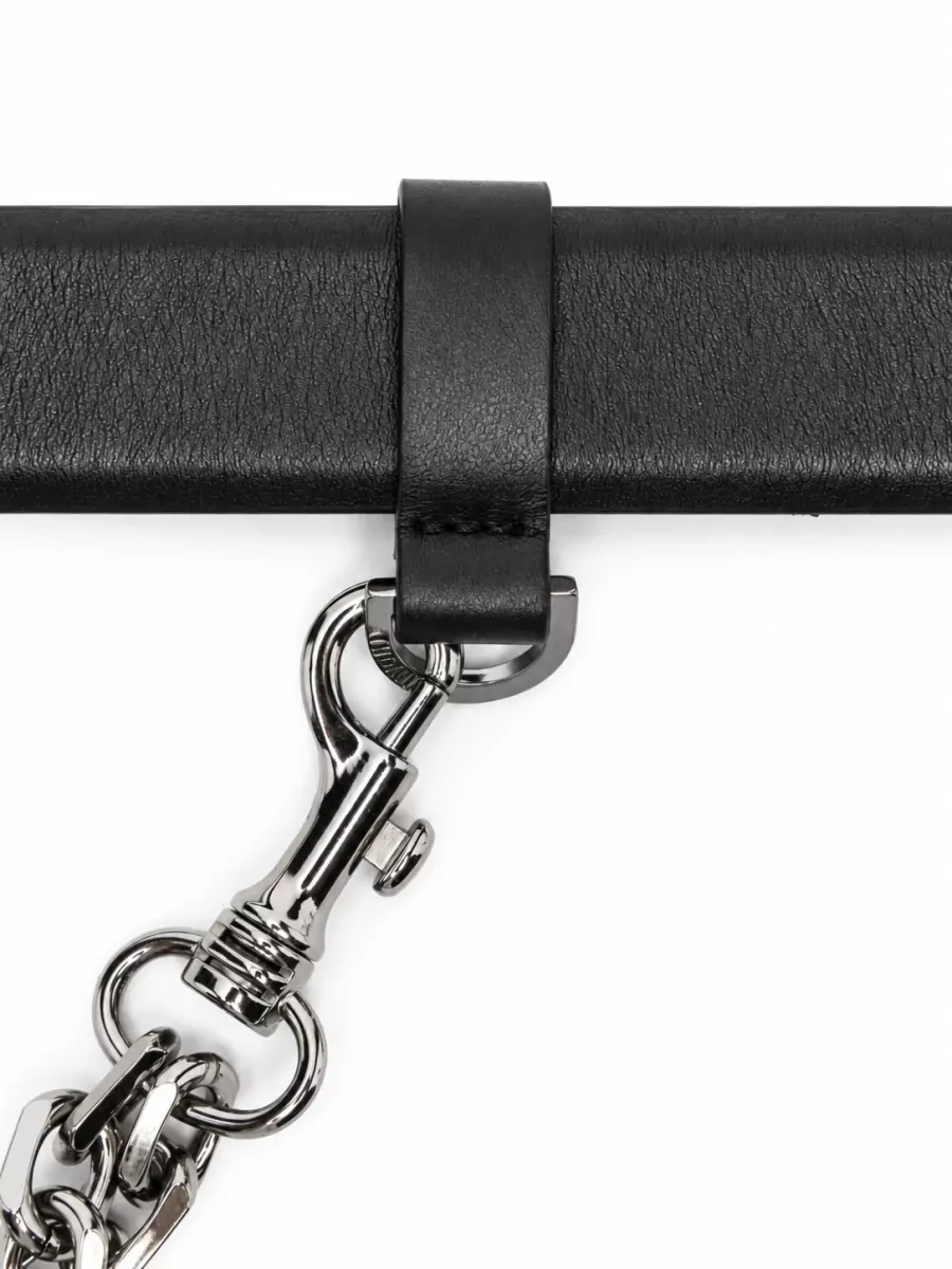 The Attico Leather belt — The black leather belt with silver chain detail reinforces the waist focus of the high-rise pant and subtly ties into the metallic hardware of the boots and bag.