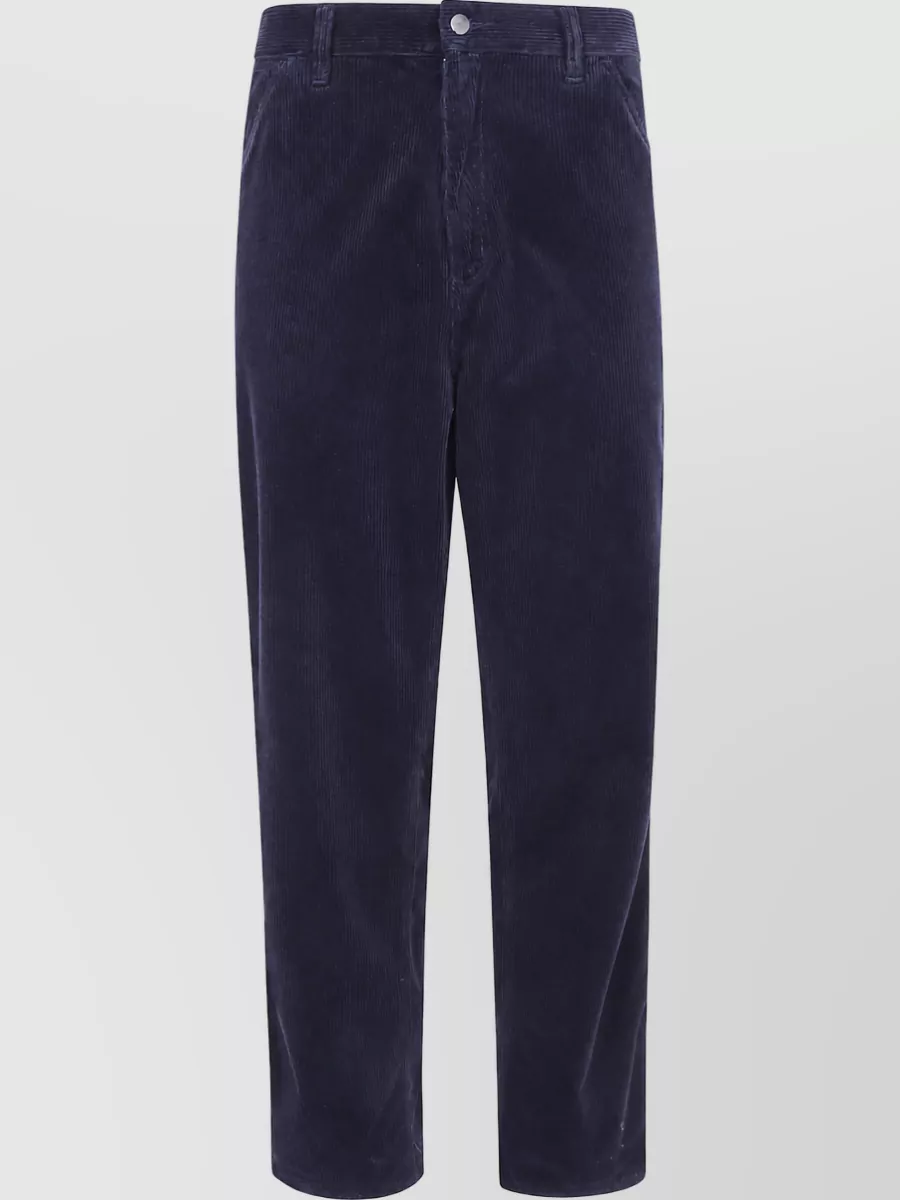 Carhartt Wip Corduroy straight-leg trousers — The straight-leg navy cord grounds the plum shirt with a cool, graphic contrast, keeping the silhouette clean and workwear-driven without introducing competing warm browns.