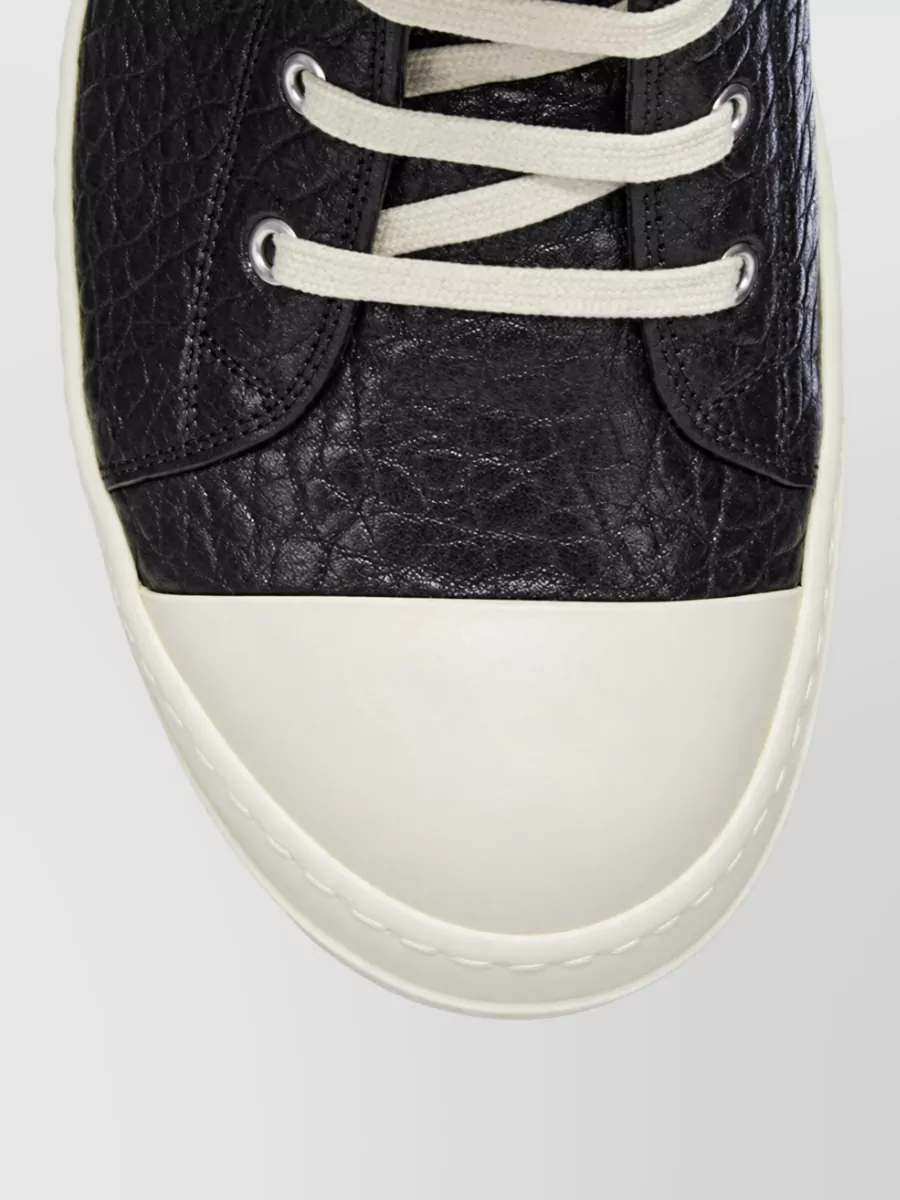 Rick Owens Leather sneaker boots — The classic black high-top sneaker boot with contrast sole grounds the midi skirt with Rick’s signature grunge edge while keeping the monochrome story tight.