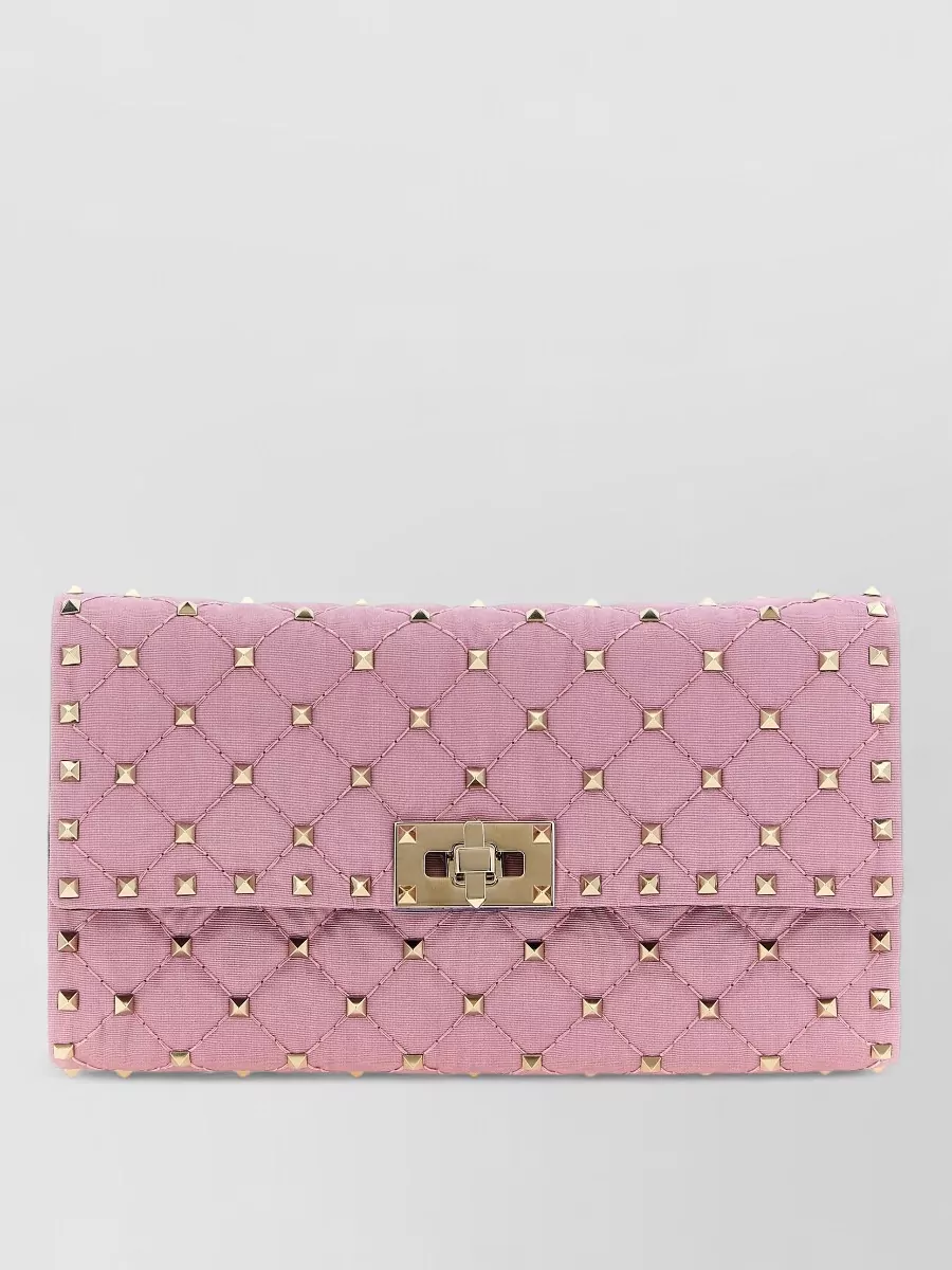 Valentino Garavani rockstud spike quilted clutch bag — The Valentino quilted pink clutch mirrors the romantic, high-glam mood and pink story while its slim shape and studded hardware add just enough attitude without overwhelming the column dress.