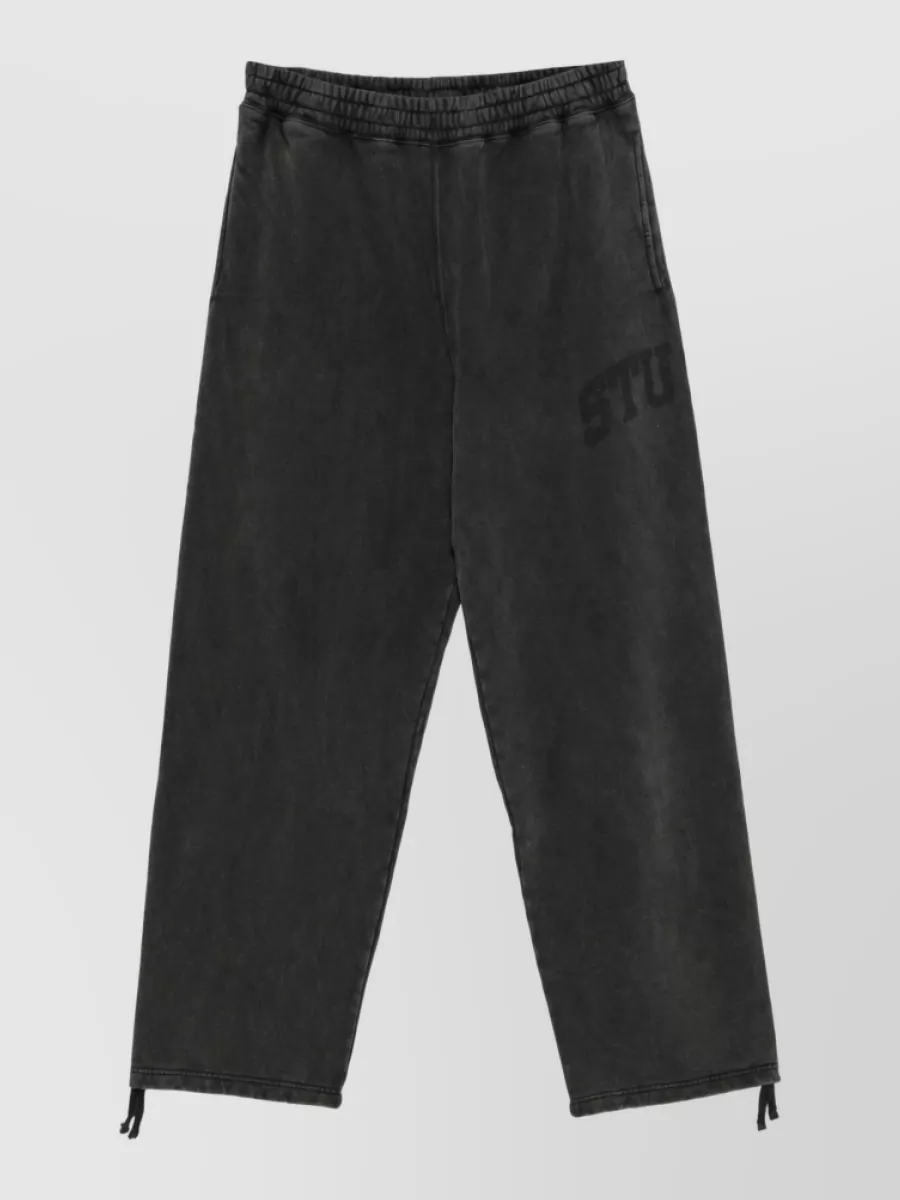 Stüssy Straight-leg trousers — The washed black Stüssy sweats keep the streetwear story consistent with the crewneck, balance the regular fit up top with a relaxed jogger silhouette, and suit the cool-weather palette and formality.