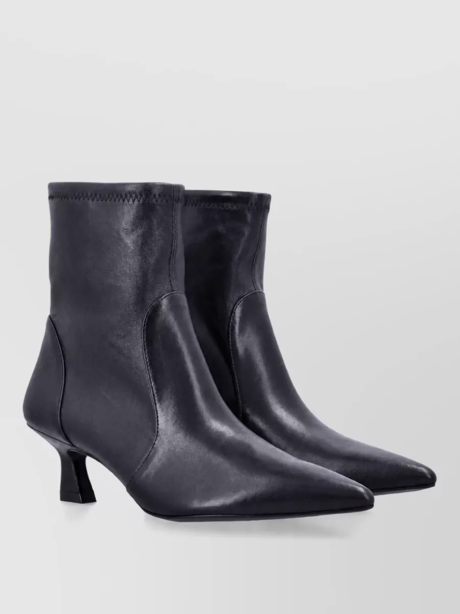 Stuart Weitzman Lamb leather ankle boots — The sleek pointed-toe Stuart Weitzman ankle boot with a subtle kitten heel feels polished but walkable, elongating the leg against the mini skirt while matching the quiet-luxury tone.