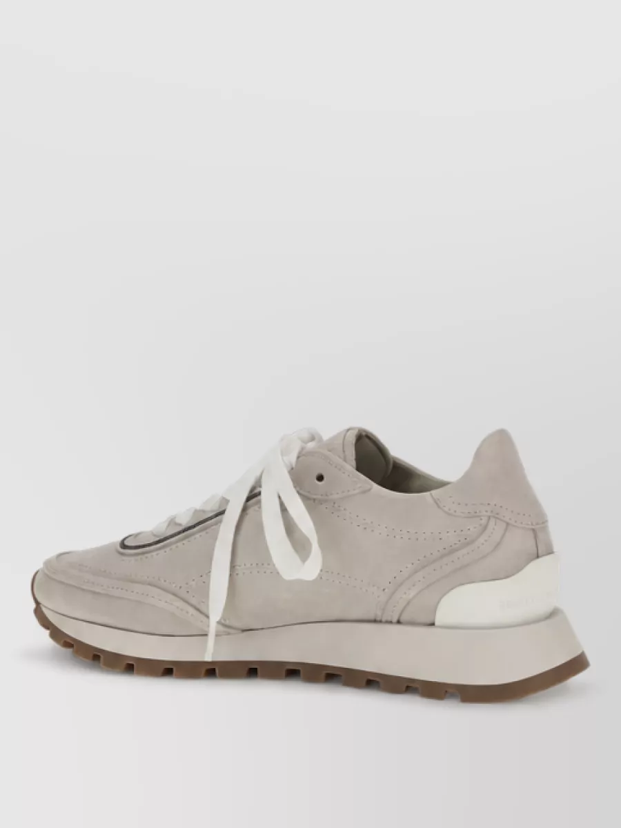 Brunello Cucinelli Leather sneakers — The warm stone suede runner echoes the soft neutrals of the tee while its sleek profile and light sole keep the outfit refined rather than overtly sporty.