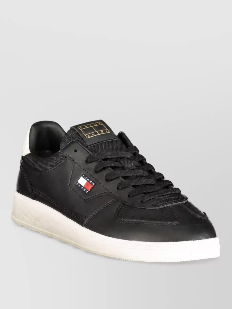 Tommy Hilfiger Polyurethane sneakers — The low-profile black sneakers with an off-white sole tie into the hoodie’s washed charcoal while keeping the outfit grounded, modern and sport-driven without feeling heavy.