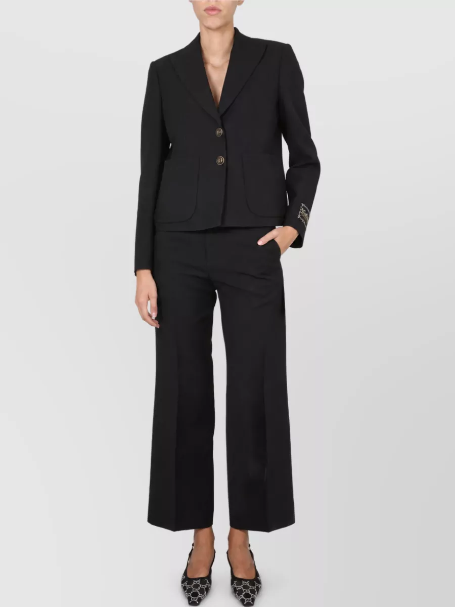 Gucci Single-breasted blazer — The cropped black Gucci blazer mirrors the trouser’s minimalist tailoring and slit detail, creating a sharp, all-black column with a subtly modern proportion that stays firmly in the quiet-luxury lane.