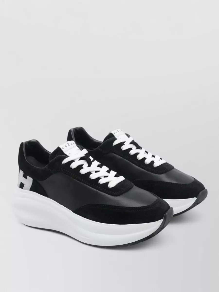 Hogan Leather low-top sneakers — The black Hogan runner keeps the mood sporty yet refined, echoing the hoodie’s athletic edge while grounding the charcoal dress in a cohesive dark-neutral palette.
