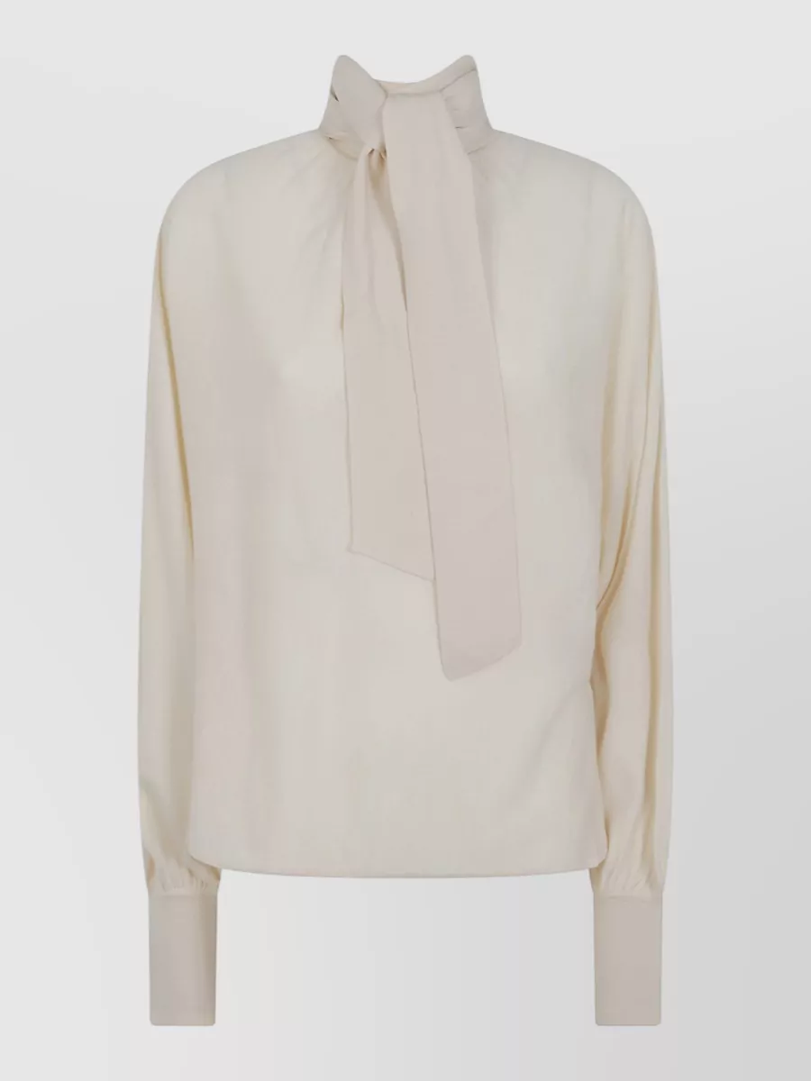 Zimmermann Merino wool tie neck sweater — The cream bow‑neck blouse softens the tailored flared trouser with quiet contrast while keeping the formality and Zimmermann sophistication aligned for gallery-to-dinner dressing.