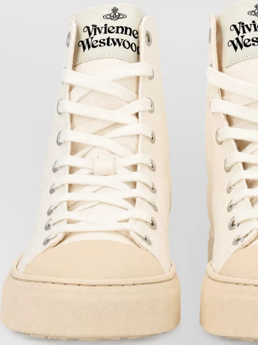 Vivienne Westwood High-top sneakers — The low-profile soft white sneakers stay clean and subtle under the mini, reinforcing the relaxed preppy mood without competing with the tee’s Orb detail.