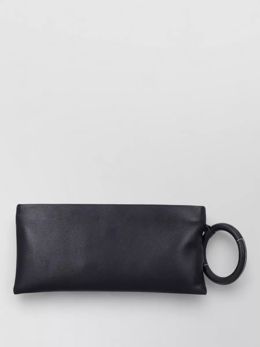 Tom Ford aura leather clutch bag — The Tom Ford ring‑handle clutch echoes the sculptural, directional mood of the boots while keeping the palette pure black with subtle metal, reinforcing a high‑tier, night‑ready minimalism.