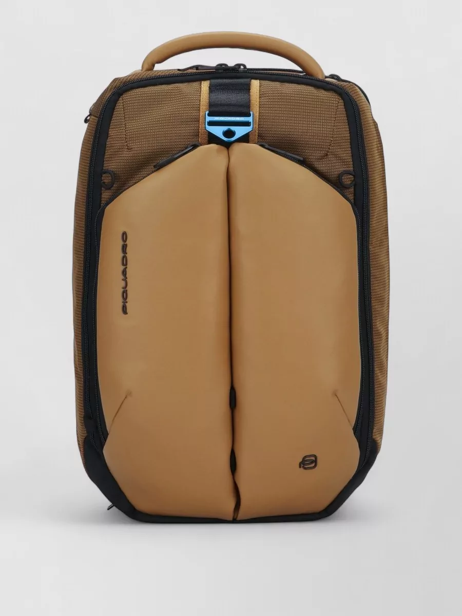 Piquadro Laptop backpack — The tan and khaki Piquadro backpack echoes the parka’s utility aesthetic and earth tones, reinforcing the functional, commuter-ready story without adding visual noise.