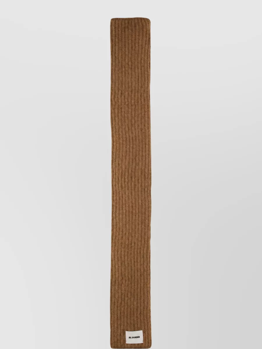 Jil Sander Scarf — The camel Jil Sander ribbed scarf in F quietly repeats the cardigan’s warmth, adding vertical texture and seasonal practicality while preserving the restrained, monochromatic feel.