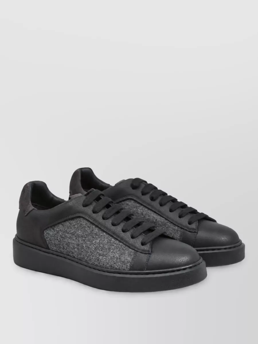 Doucal's Leather sneakers — The Doucal’s black and grey sneaker matches the palette and quiet-luxury mood while keeping the set modern and relaxed rather than overly formal.