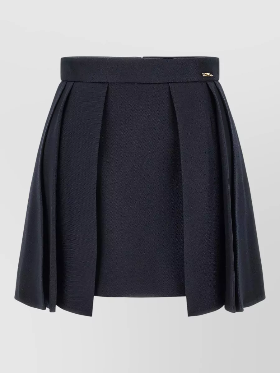 Elisabetta Franchi Virgin wool high-rise pleated mini skirt — The high-waisted navy pleated mini mirrors the knit’s maritime gold-button detailing and keeps a cohesive preppy palette while giving a flattering, leggy A-line balance to the cropped top.