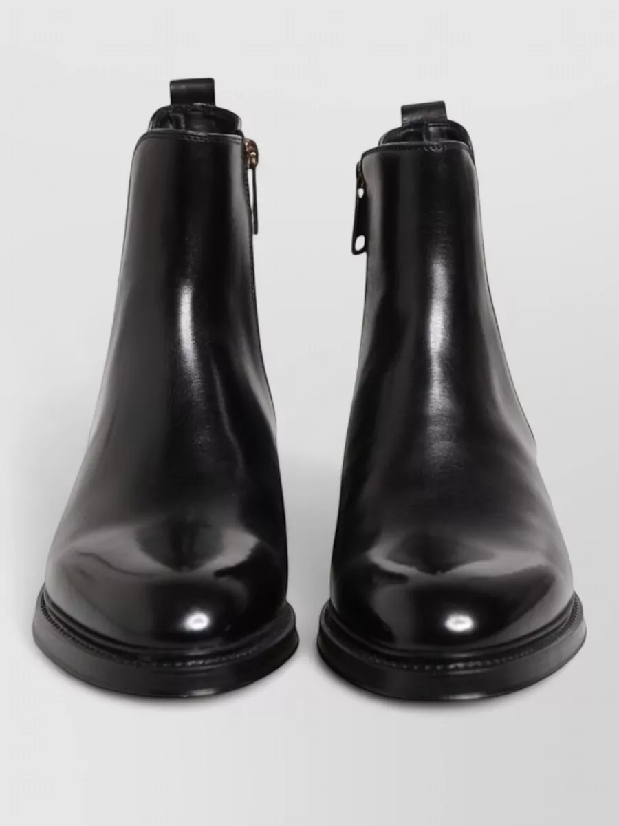 Dolce&Gabbana Leather chelsea boots — The sleek black Chelsea boot gives a clean, elongated line that suits formal tailoring and visually continues the black of the coat without adding extra pattern or bulk.