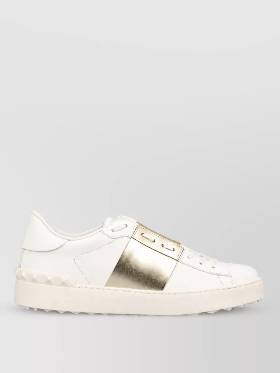 Valentino Garavani Leather low-top sneakers — The off-white sneaker with pale gold detail keeps the outfit relaxed yet refined, picking up the crystal shine at the neckline without competing or adding heaviness.
