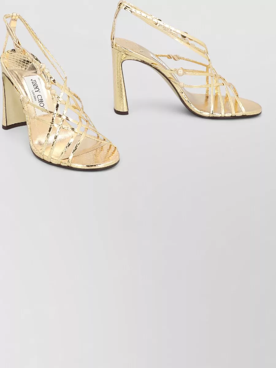 Jimmy Choo Leather heeled sandals — The Jimmy Choo metallic gold strappy sandal echoes the bag’s hardware and the dress’s warm tones, leaning into a Y2K club mood while staying polished and season-appropriate for night.