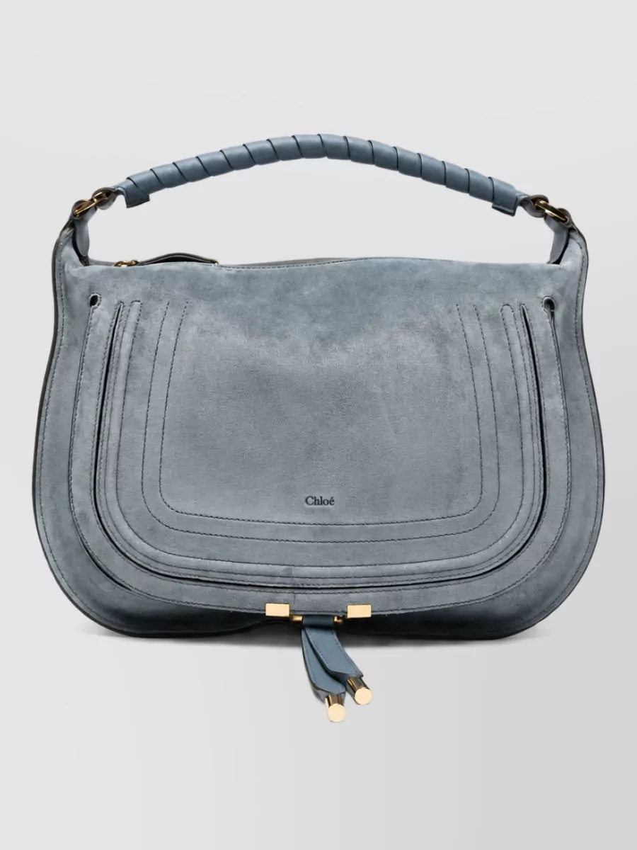 Chloé Medium leather clutch bag — The slate-blue suede Chloé saddle clutch sits in the same tonal family as the dress and jacket, maintaining quiet-luxury polish while the curved shape reinforces the romantic, soft-structured vibe.