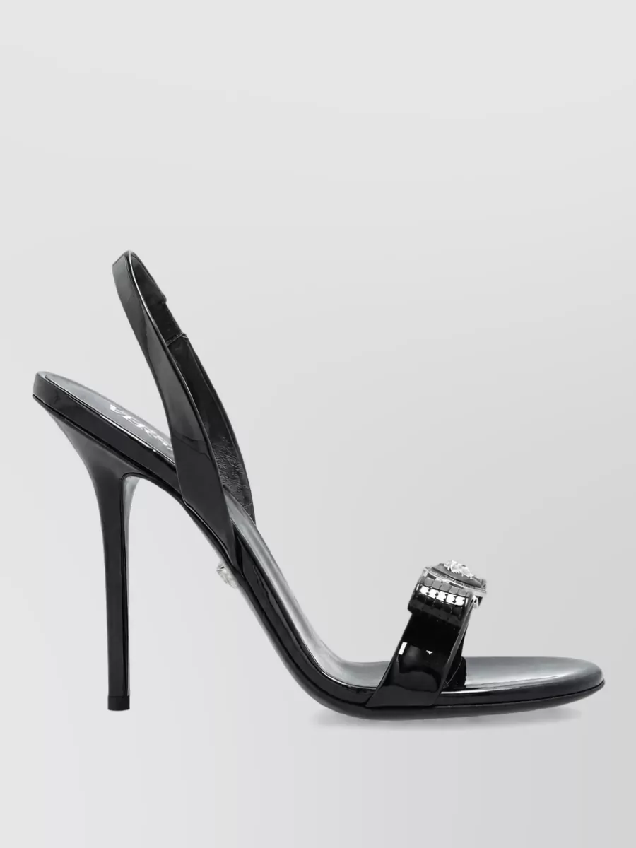 Versace Leather slingback sandals — The black Versace slingback stilettos amplify the tee’s after-dark, concert vibe and work perfectly with the flared trouser to elongate the leg while keeping the palette sleek.