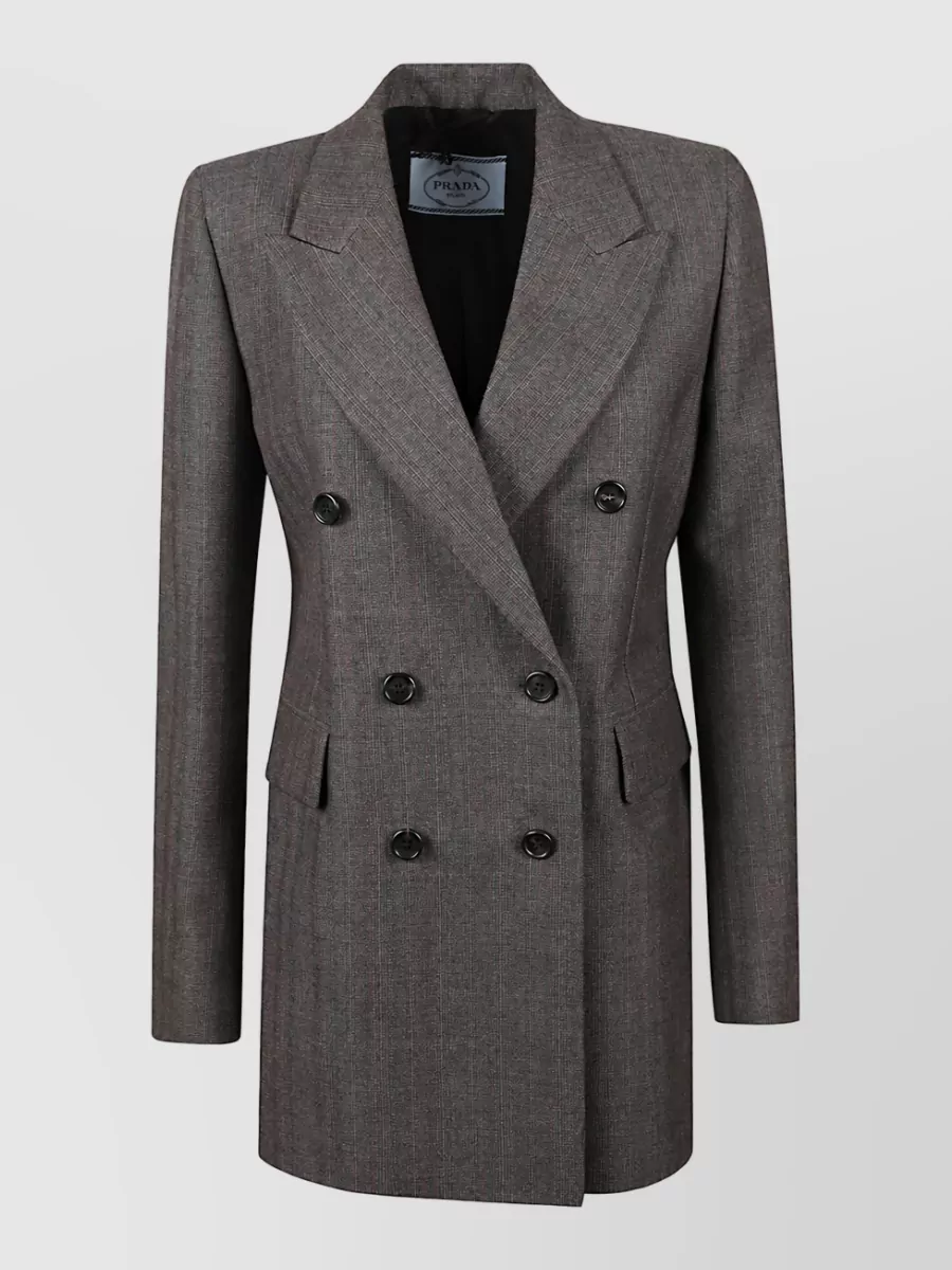 Prada Pinstripe suit jacket — The double-breasted checked charcoal blazer reinforces the tailored black trouser’s sharpness, keeping the palette dark and formal while the longline cut creates a clean, elongated column.