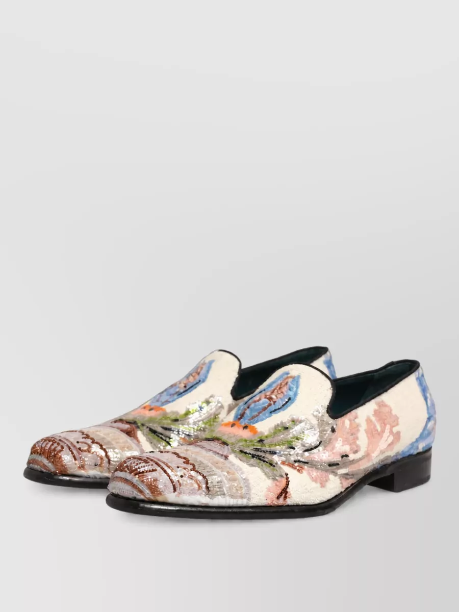 Dolce&Gabbana Sequin embroidered slippers — The sequinned floral ivory slipper echoes the shirt’s ornate romance and lightness while still reading formal, tying top and bottom together against the clean black trouser.