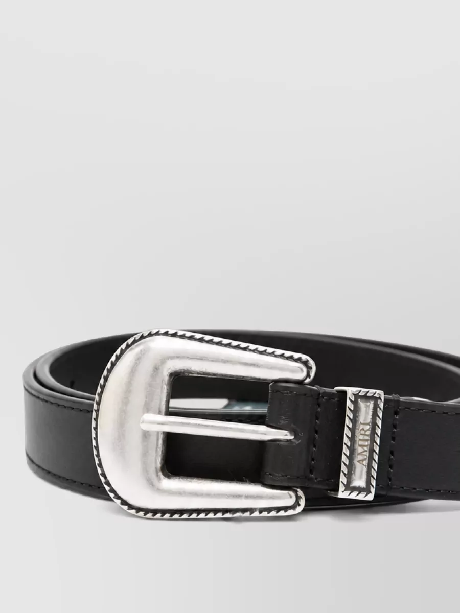 Amiri Leather western belt — The black leather belt with brushed silver Western buckle quietly reinforces the LA rock story and sharpens the waistline so the relaxed boxy tee reads intentional over the slim jeans.