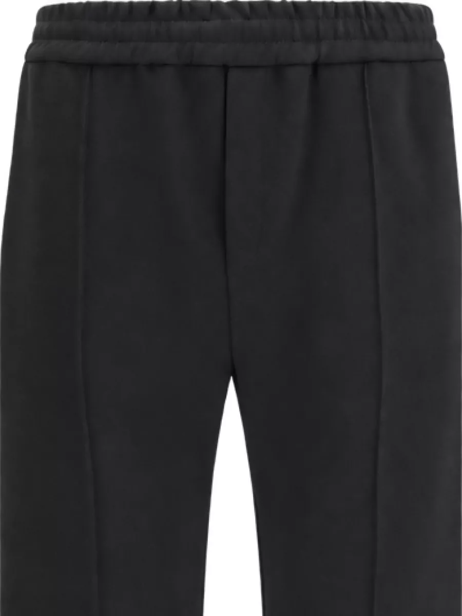 Valentino Cotton pleated track pants — The black Valentino tapered track pant matches the source piece’s streetwear‑meets‑tailored mood and keeps the silhouette clean and streamlined without breaking the monochrome story.