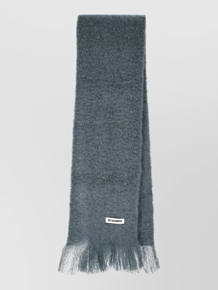 Jil Sander Scarf — The slate blue-grey brushed scarf layers tonally with navy and charcoal, adding texture and warmth without breaking the restrained minimalist palette.