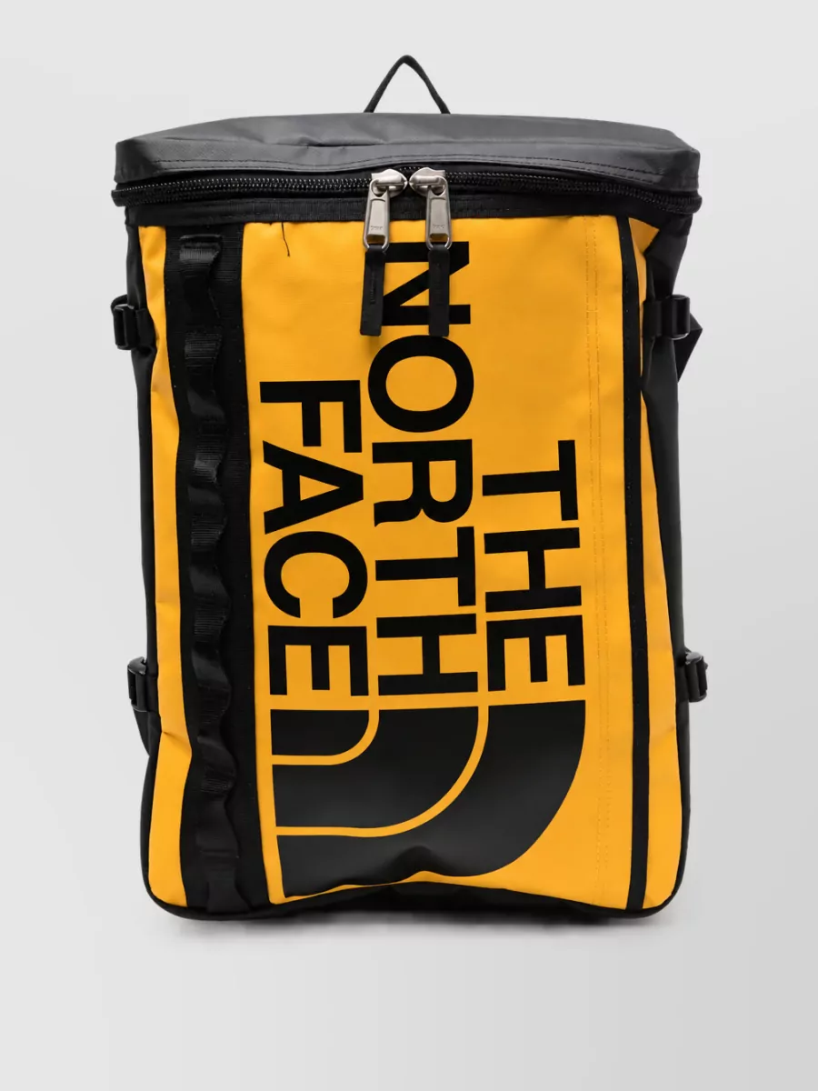The North Face Base camp fuse box travel bag — The North Face mustard and black backpack picks up the hoodie’s soft yellow graphic and keeps the vibe sporty and practical without breaking the monochrome-and-denim palette.