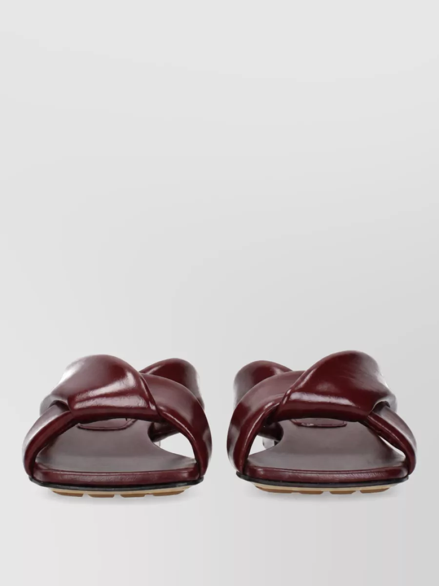 Bottega Veneta Leather sandals — The Bottega flat oxblood slides echo the burgundy of the trouser in a slightly darker register, keeping the outfit relaxed yet polished and perfectly proportioned to the wide leg.