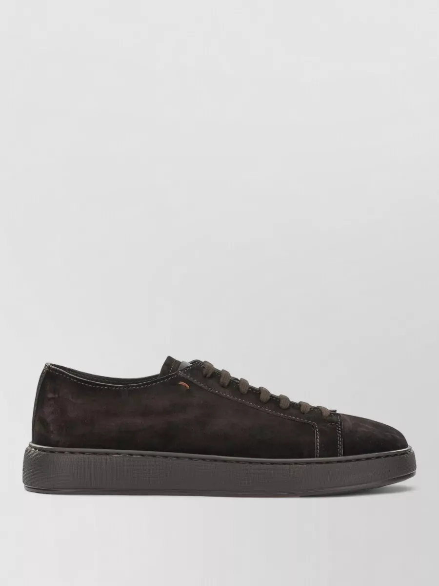 Santoni Suede low-top sneakers — The dark suede Santoni sneaker echoes the tee’s black and the denim’s wash, giving a refined but relaxed finish that suits the minimalist, quiet‑luxury mood better than bright white or overtly sporty runners.