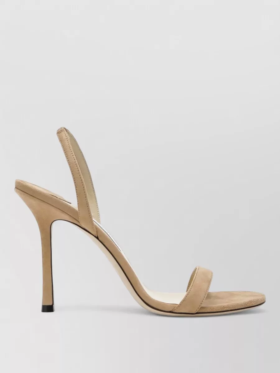 Jimmy Choo Sandals — The nude Jimmy Choo slingback keeps the palette soft and elongated against the chocolate dress and tan bag, adding dressy polish without visually cutting the leg.