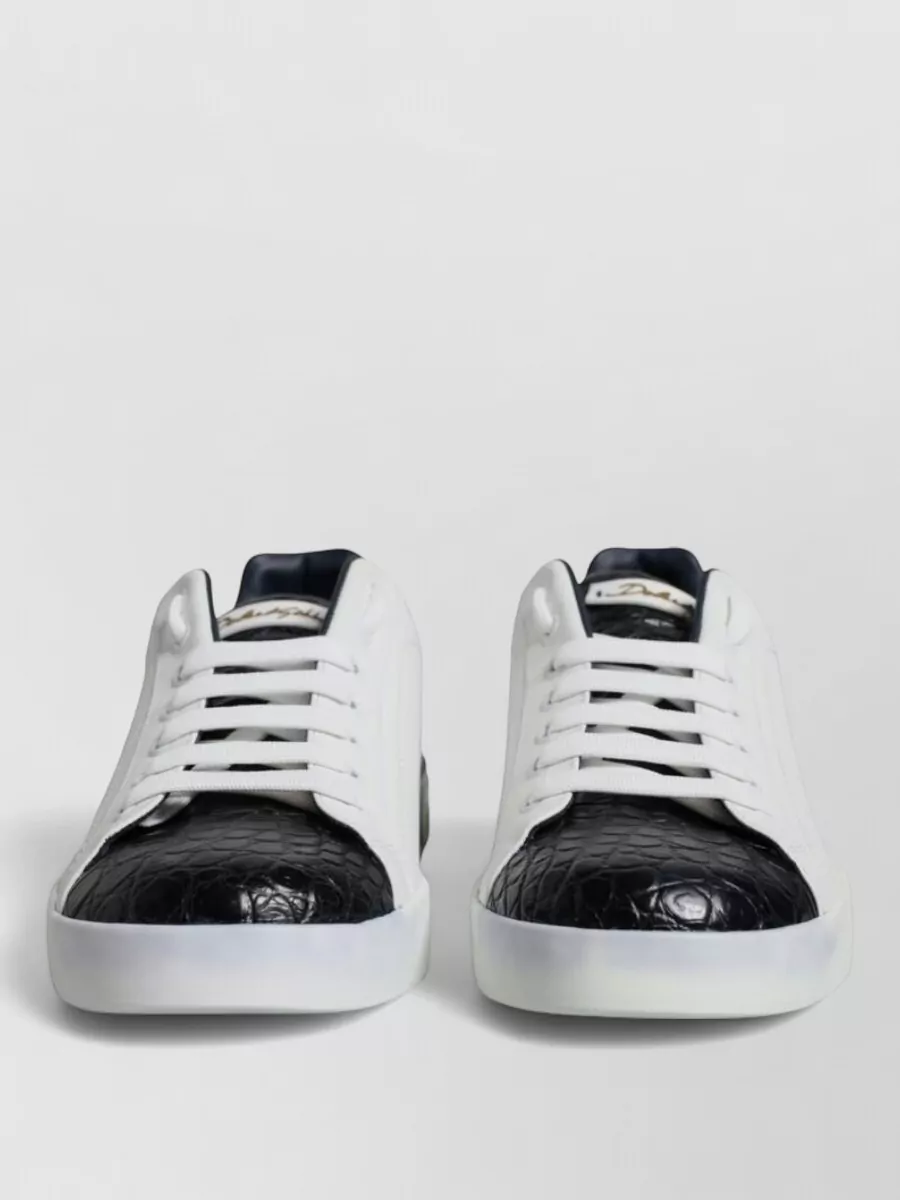 Dolce&Gabbana Leather low-top sneakers — The white low-tops with black croc toe echo the polo’s dark tones, feel luxe and graphic, and keep the overall mix refined rather than overly logo-heavy.