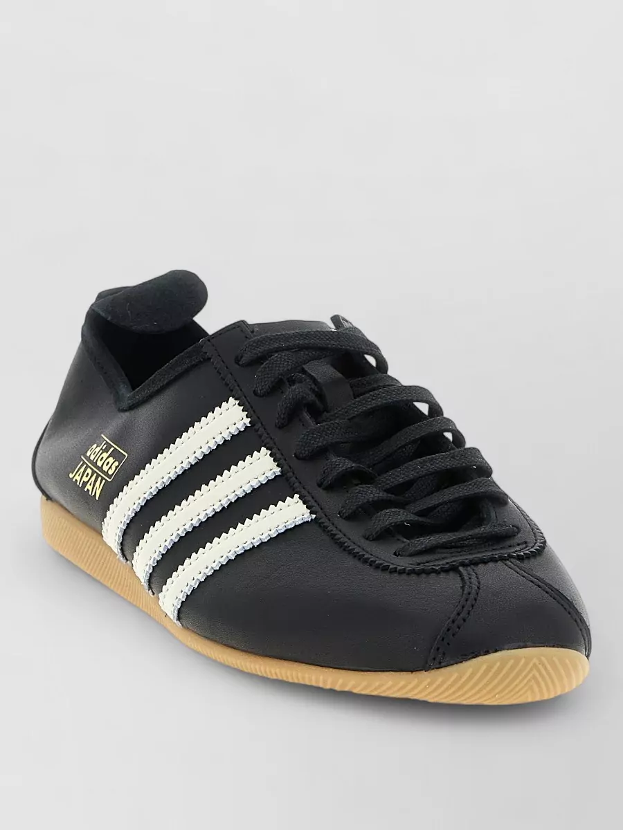 Adidas Originals Leather low-top sneakers — The Adidas black low-top with ivory stripes and gum sole echoes the leggings’ sleek line, keeps the palette tight, and adds a subtle retro-sport edge that suits off-duty city wear.