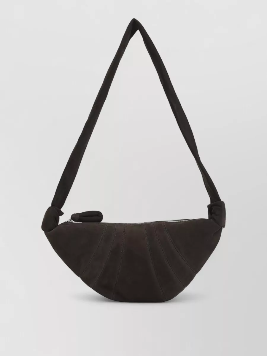 Lemaire Leather small croissant shoulder bag — The black crescent shoulder bag repeats the dark leather of the shoes and its curved, sculpted shape sits neatly against the body, in tune with the quiet, tailored mood.