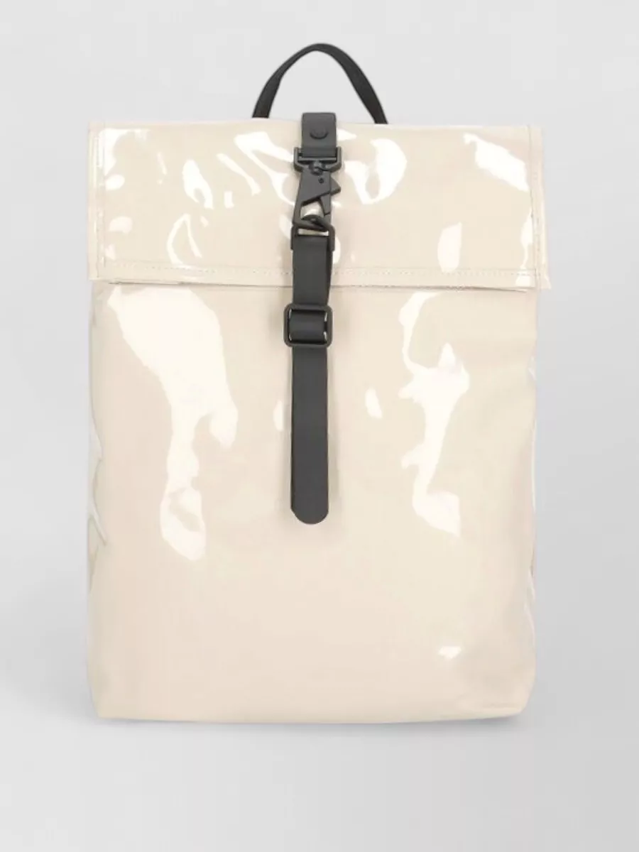 Rains Rolltop backpack — The cream-and-black structured backpack echoes the jacket’s urban utility feel and light neutrals, giving a coherent, weather-ready finish for day-in-the-city wear.