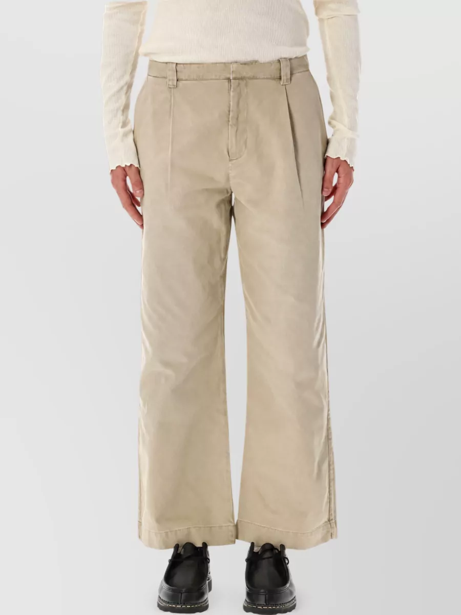 Our Legacy Wide-leg chino trousers — The cropped charcoal tailored trouser sharpens the striped buttercream shirt, keeping the palette muted and the formality in that smart-casual zone the piece is designed for.