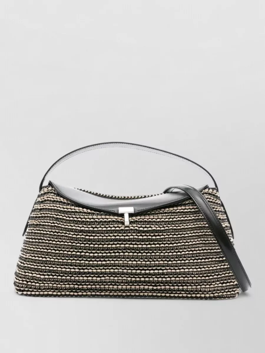 Totême Leather shoulder bag — Bag A’s structured woven trapeze shape and black leather framing introduce subtle texture while harmonising with the monochrome palette and polished but relaxed mood.