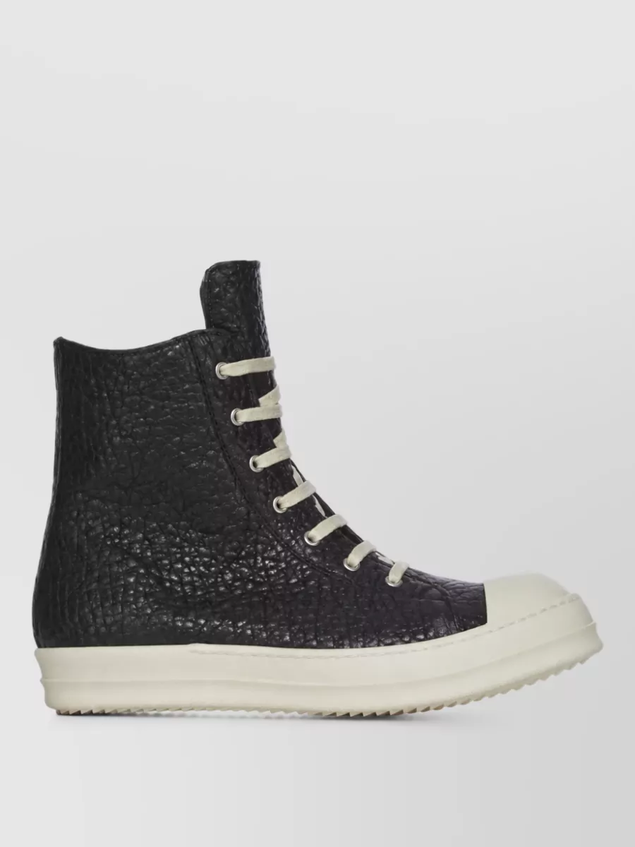 Rick Owens Leather sneaker boots — Rick Owens high-top sneaker boots in black and off-white echo the hem-pooling drama of the dress and stitch language of the jacket, grounding the length with a strong, graphic platformed profile.