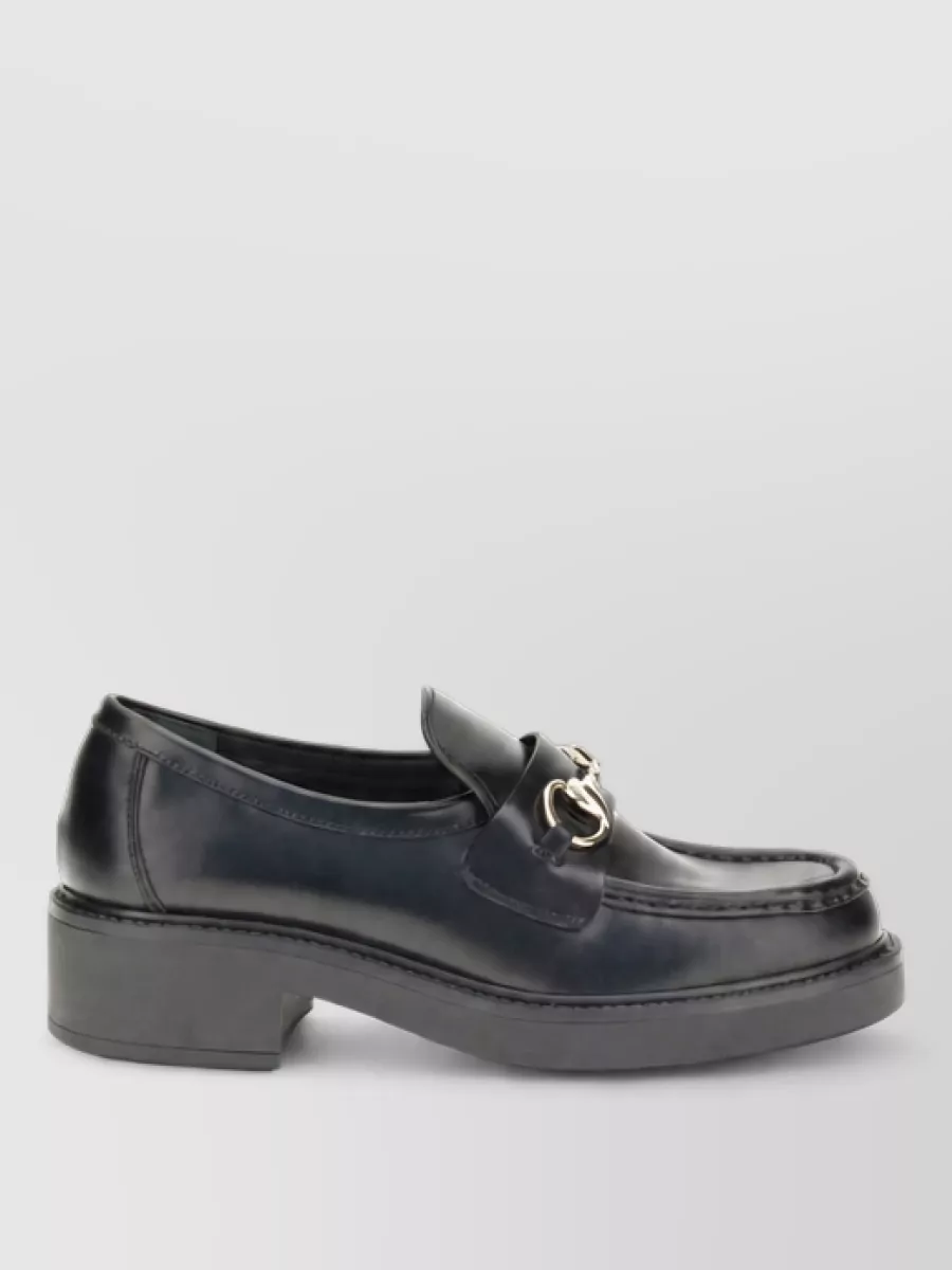Gucci Leather slip-on loafers — The Prada black ankle boot with a clean pointed toe and block heel is the most polished option to ground the wide-leg trouser, adding height and maintaining the power-suiting attitude.