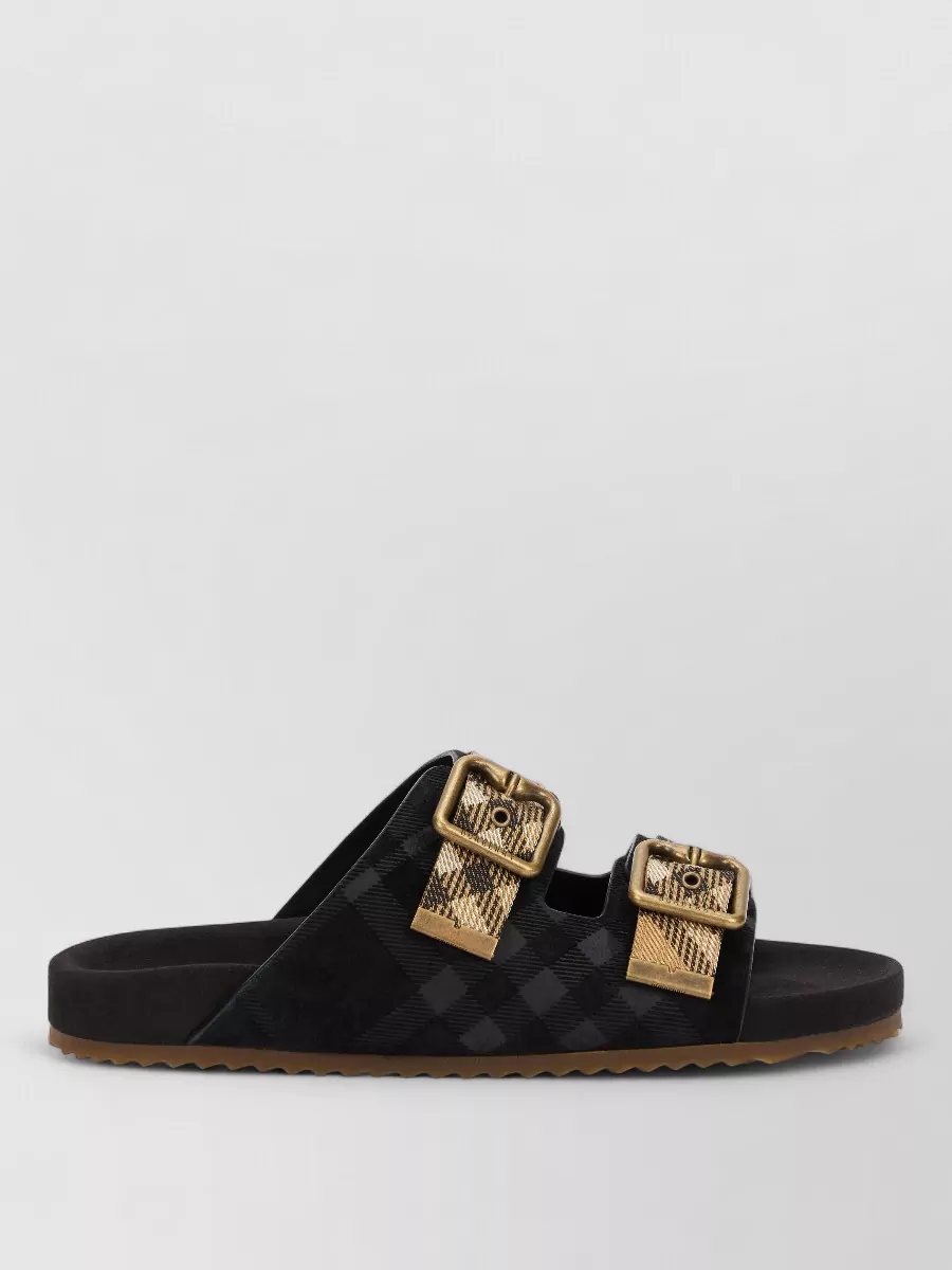 Burberry Leather buckled sandals — The flat slide sandal in classic check and neutrals keeps the look relaxed yet polished, echoing the Burberry pattern at the hem without overpowering the dress-and-waistcoat combination.