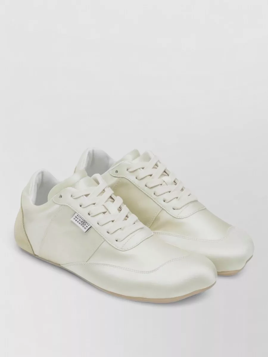 Mm6 Maison Margiela Satin low-top sneakers — The off-white canvas sneakers echo the tee’s purity and the stone trouser tone, keeping the outfit relaxed and gallery-ready within Margiela’s quiet luxury language.