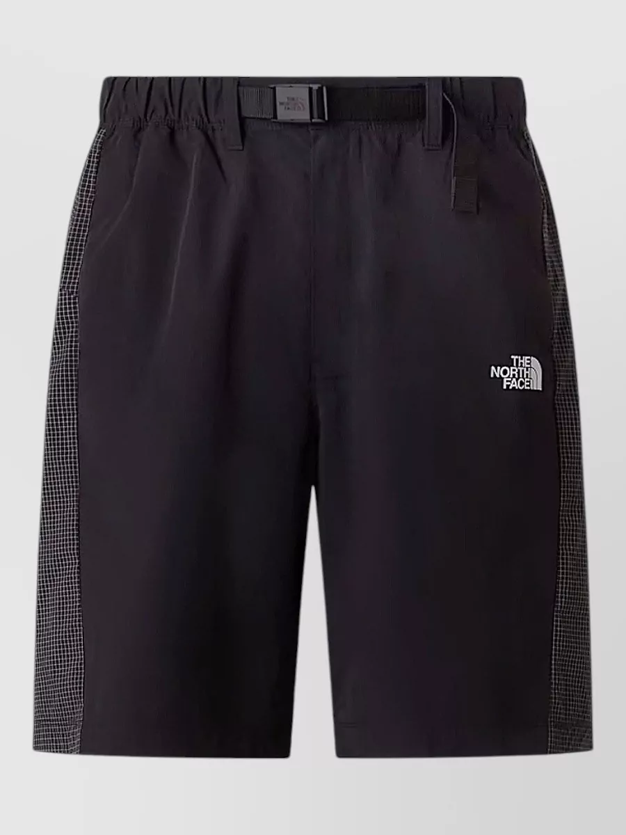 The North Face Nylon belted bermuda shorts — Short A’s black technical fabric and clean regular cut match the jacket’s outdoor-urban utility, giving a balanced proportion and a subtle contrast to the navy.