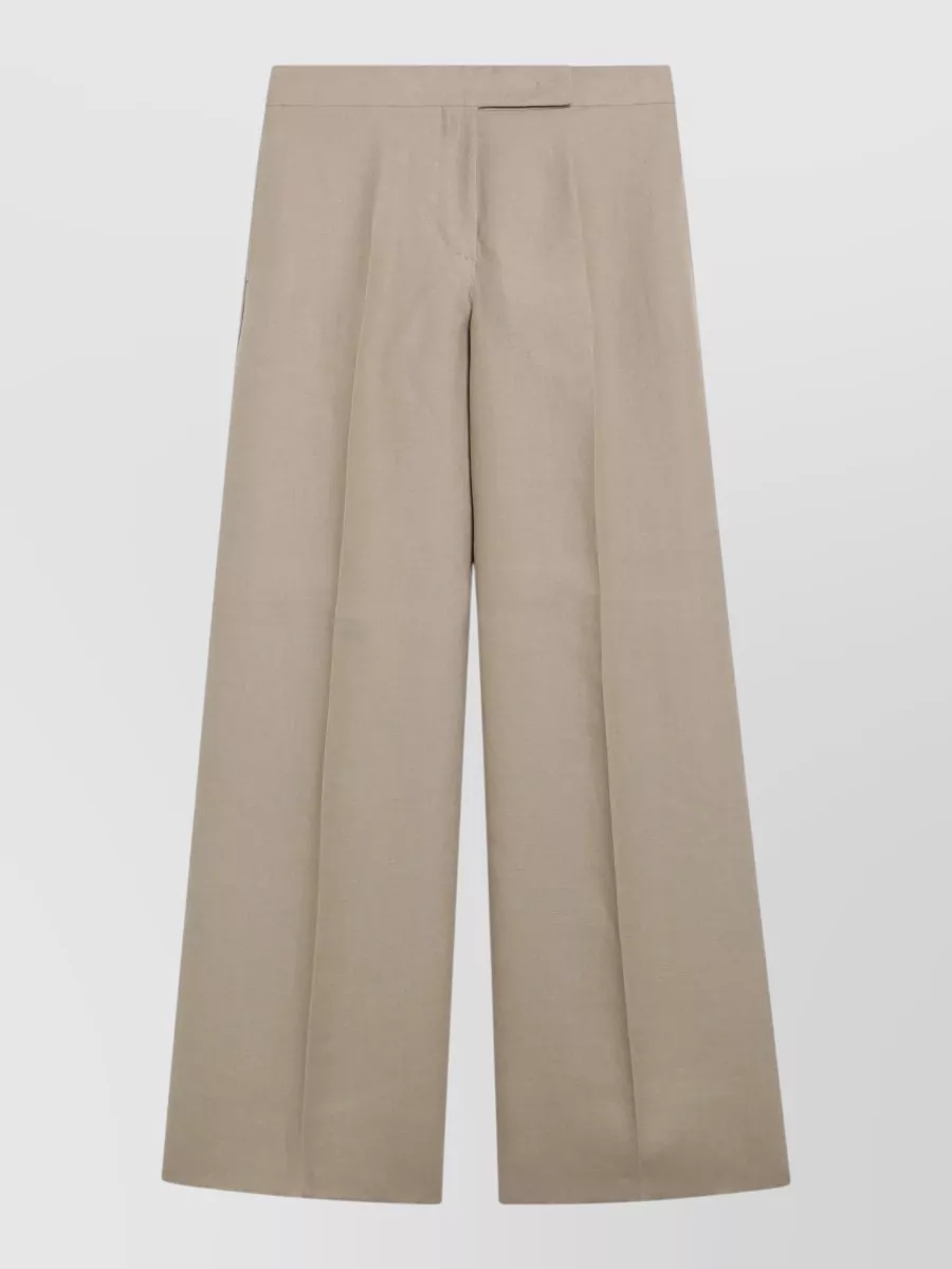 Max Mara Tailored trousers — The high-waisted wide-leg trouser in warm taupe mirrors the waistcoat’s tone and tailoring level, creating a fluid monochrome column that feels refined enough for the vest worn as a standalone top.